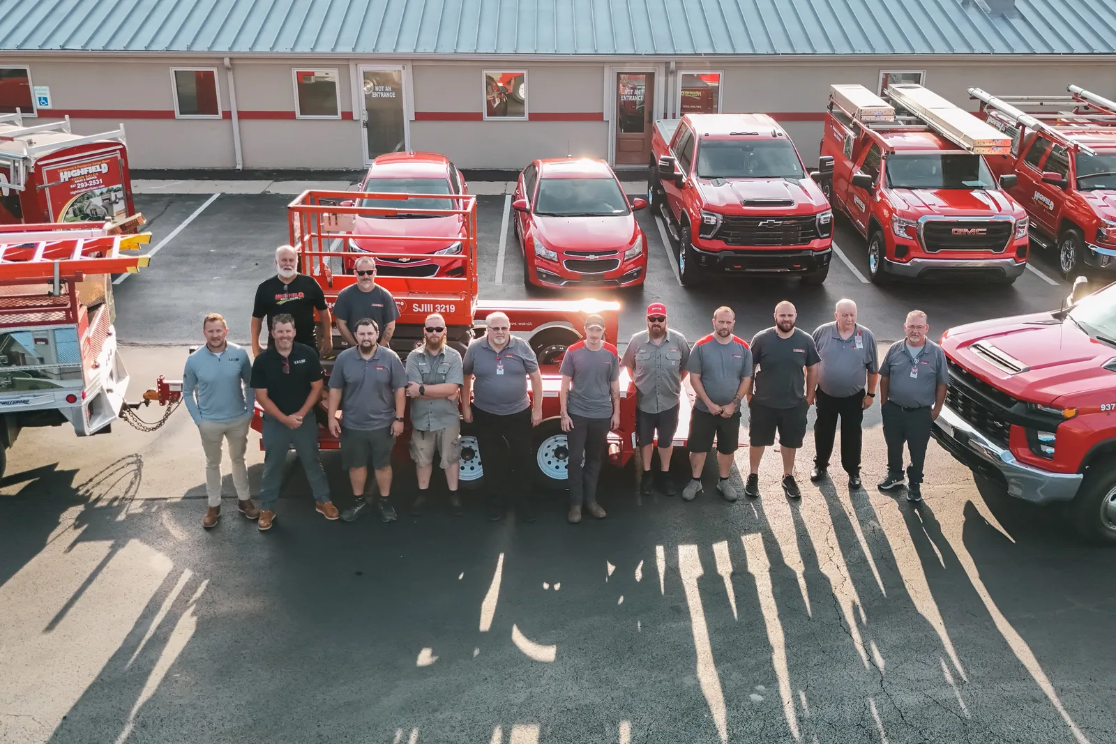 The Highfield Door Sales team standing with their red service trucks outside the Kettering, OH showroom